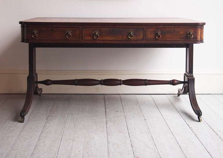 of generous proportions, the beautifully patinated mahogany top with incised corners and reeded edges, the outer edge crossbanded in rosewood, having three frieze drawers to each side and two long dummy drawers at each end, with cockbeaded edges and
