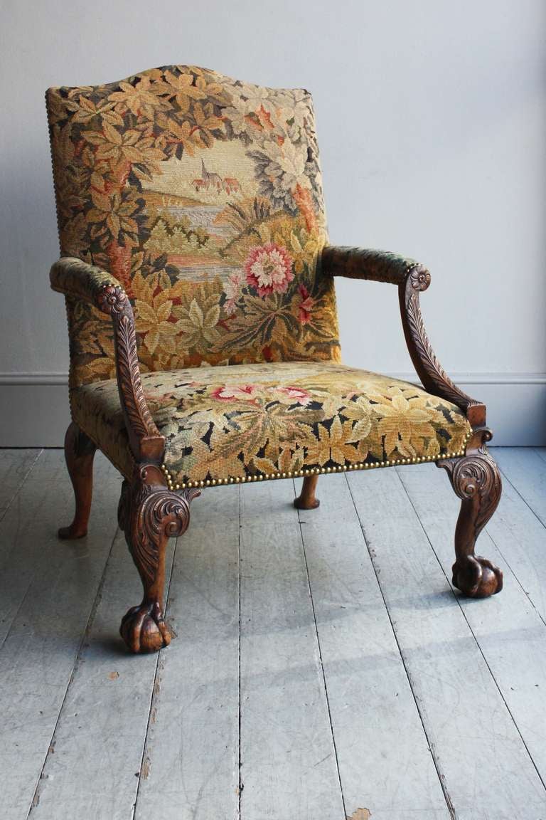 Mahogany frame, the rectangular back with shaped top, scrolling arms centered by a flower heads on downswept acanthus carved supports, raised on acanthus carved cabriole legs with bold claw and ball feet. In the manner of Giles
