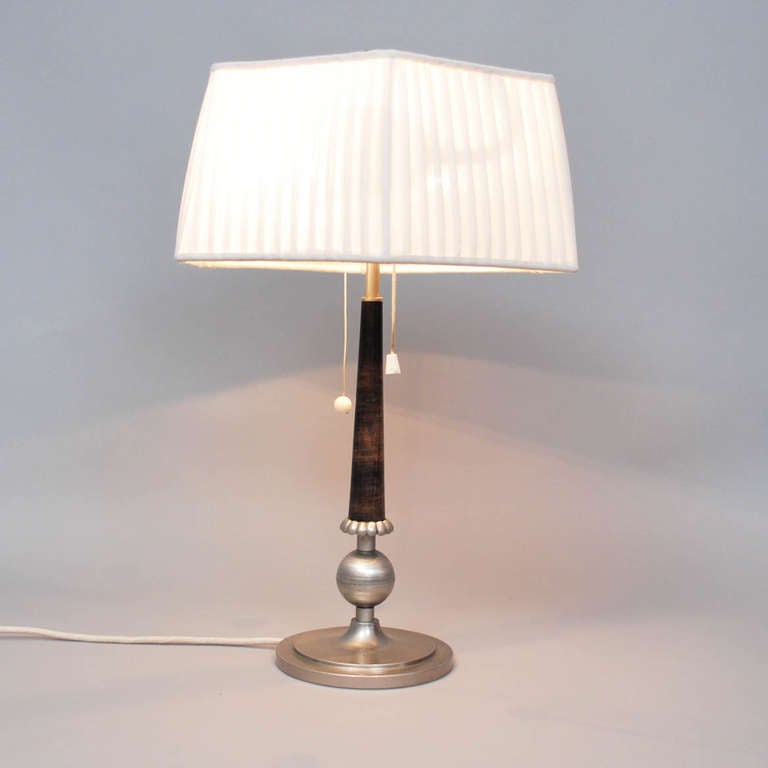 Table lamp from 1925-35, anonymous Sweden.
Tinn and stained wood. Offwhite shade reupholstered recently.