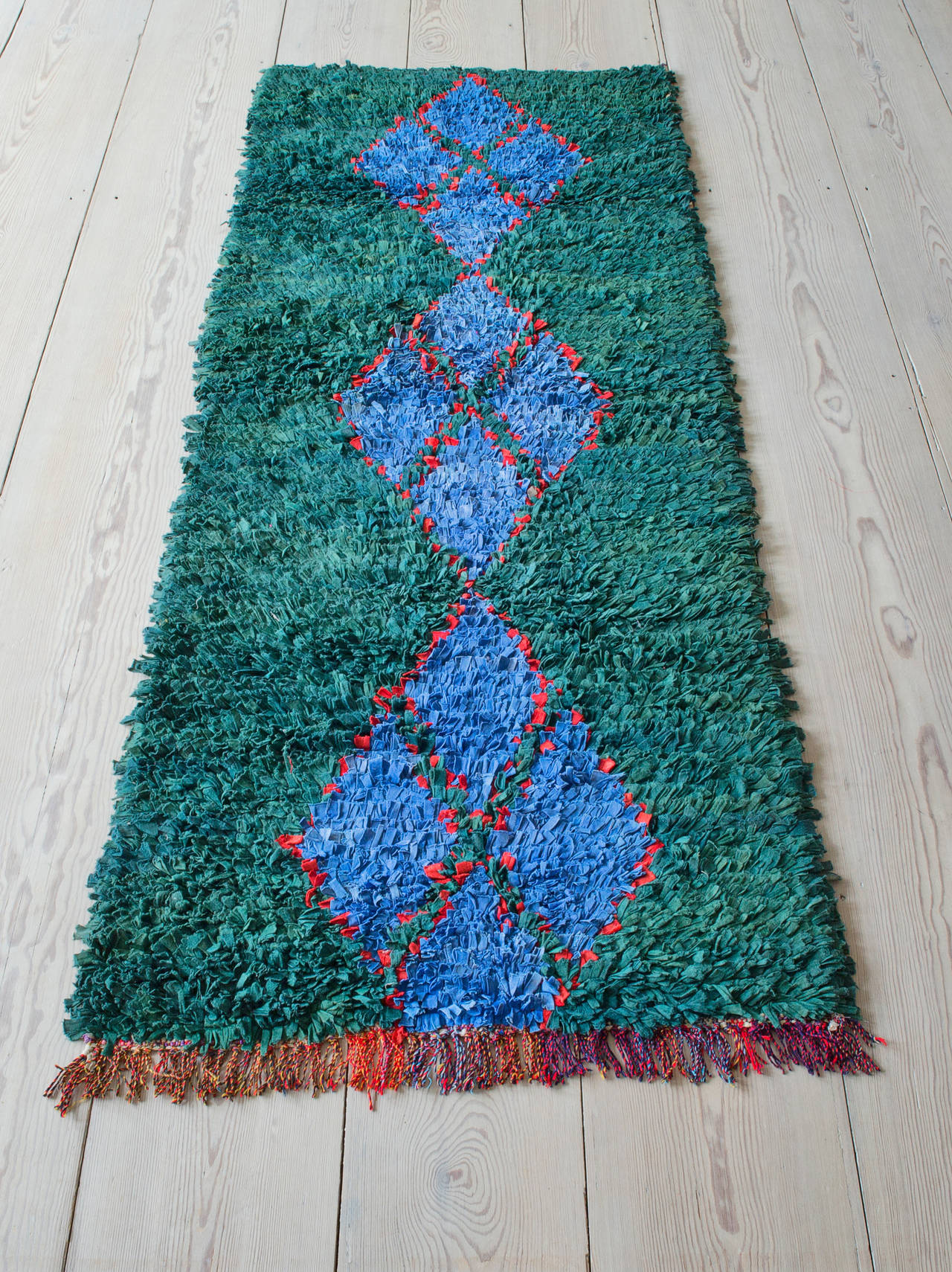 Beautiful Boucherouite rag rug. Bottle green background with a pattern in shades of blue and red.