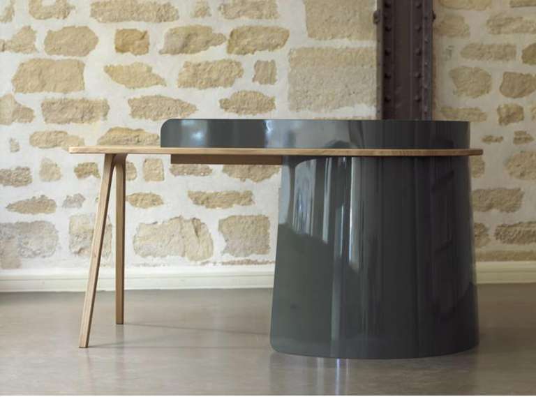 Drawing inspiration from architectural constructions using the cantilever principal, the lacquered metal skirt gives a solid volume on which the entire desk depends. This support contrasts with the light oak suspended top which juts out over an