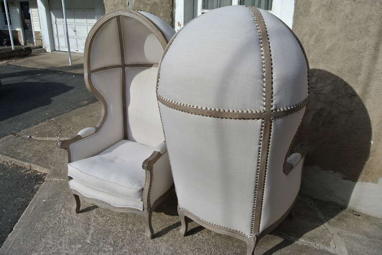 Beautiful pair of Rustic French canopy hood bishop's chairs. Faded wood frame with newly reupholstered in white linen with brass tacks.