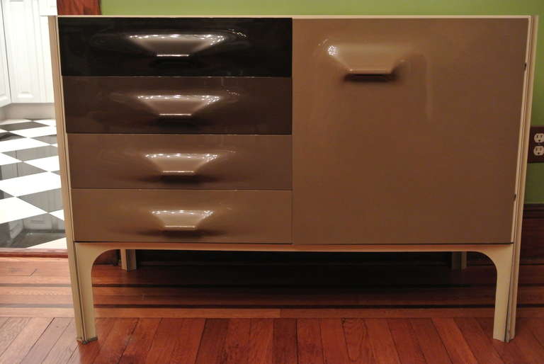 Lacquered wood with three polycarbonate drawers (two single and a double deep lower drawer.) and cabinet door with shelf inside on a steel frame.