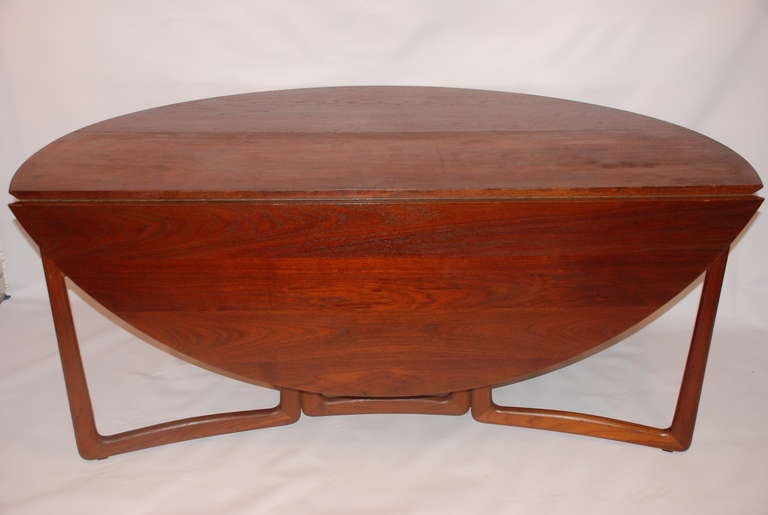 A sculptural teak dining table or console with two drop leaves.