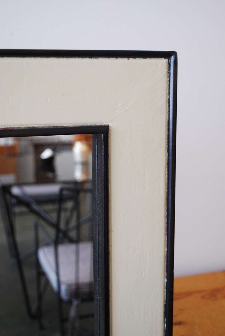 This unique, large-scale mirror designed by Paul Frankl in the late 1940s is an example of the turn of the century modern movement in its linear and simplistic design with a nod toward the Art Deco aesthetic. The frame is black-brown with off-white