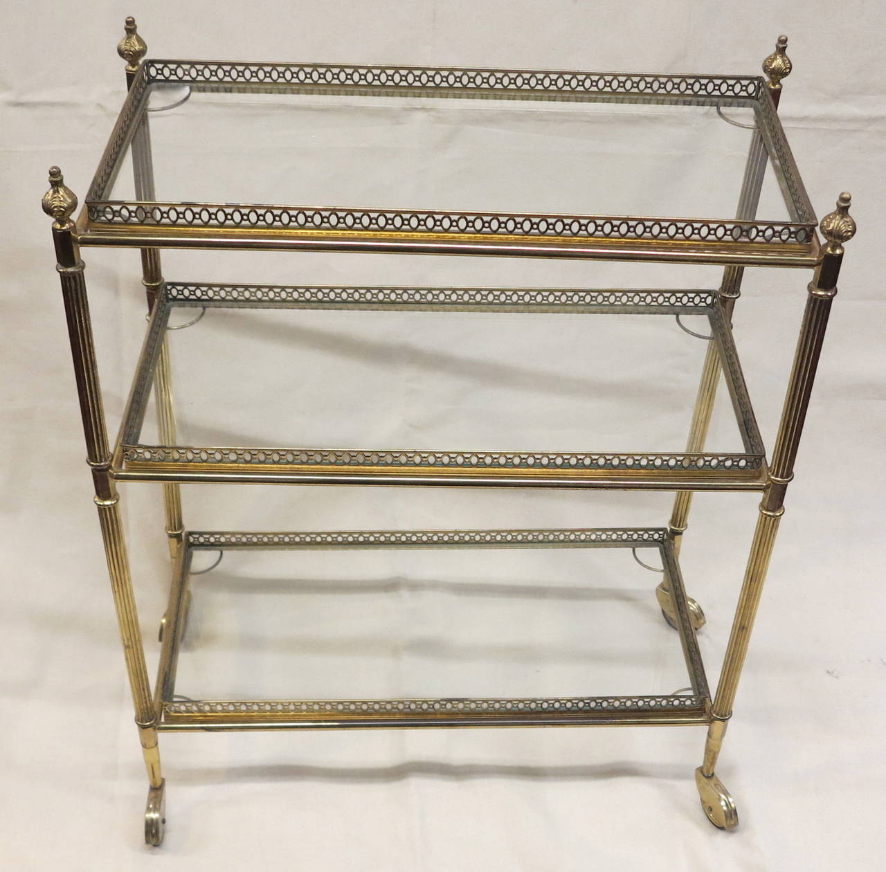Service has wheels with amounts in bronze with pine cones, 3 removable glass shelves with gallery , good condition, circa 1950-1970