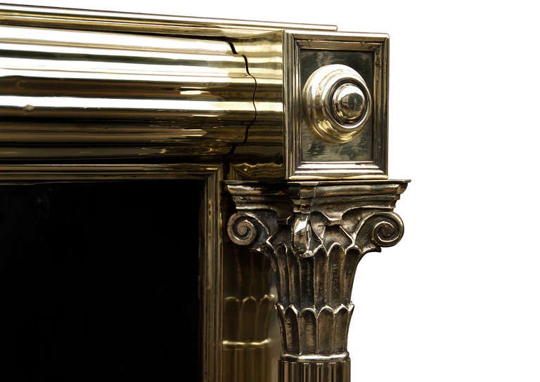 A good quality Regency brass and steel register grate. The elegant reeded columns surmounted by scroll and leaf capitals with bullseye end panel above, the pierced brass fret with decorative cast iron bars and hobs. Engraved brass finials. Back and