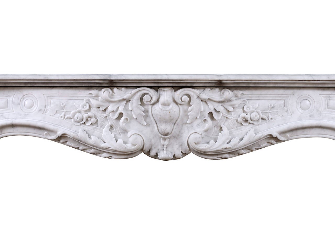 A good quality 19th century French Louis XV Carrara fireplace. The panelled frieze with heavily carved leafwork and foliage throughout. The scrolled jambs with shell, delicately carved flowers and stiff acanthus leaf below. Shaped shelf.

Measures: