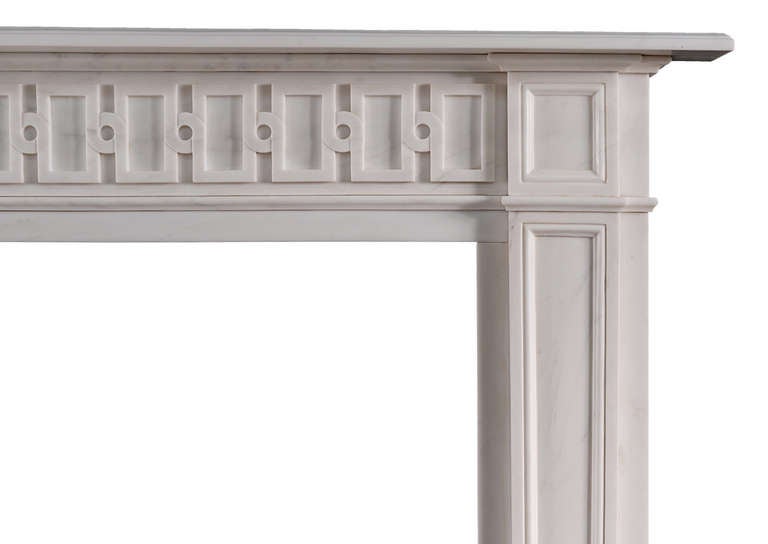 Une cheminée anglaise en marbre blanc d'inspiration Whiting. La frise (d'après un dessin original) de conception isométrique, les jambages à panneaux effilés surmontés de blocs d'angle à panneaux. Tablette moulée.

Largeur de l'étagère : 1535 mm /