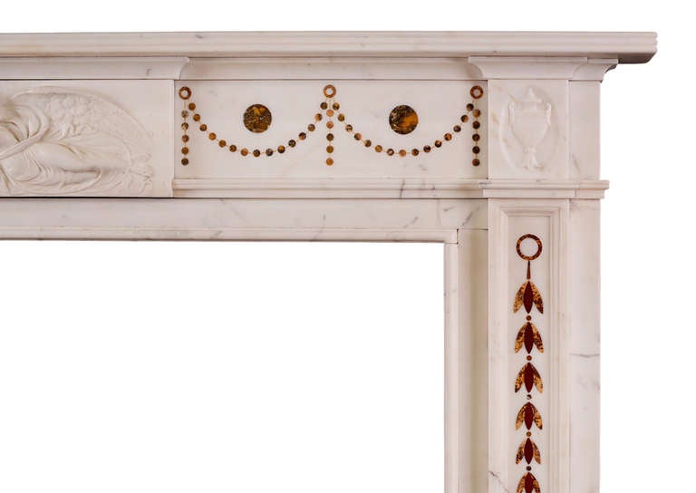 A very fine English Statuary marble fireplace with coloured marble inlay. The panelled jambs with inlaid belldrops, surmounted by carved classical urn. The frieze with inlaid Siena drapery and central carved plaque portraying Hebe feeding the Eagle