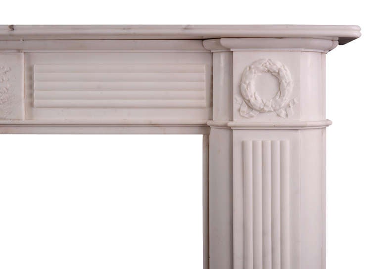 A large, period Regency statuary marble fireplace. The reeded jambs surmounted carved wreaths, tied by ribbons. The reeded frieze with carved central plaque featuring basket of fruit and foliage. Reeded shelf above. An attractive, imposing piece.