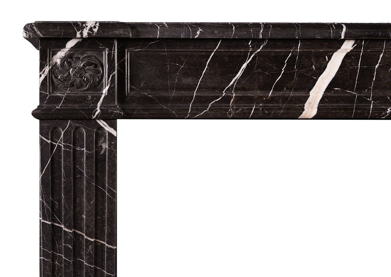 A French Louis XVI style fireplace in veined brown marble. The stop fluted jambs surmounted by carved swirling paterae to end blocks. Panelled frieze surmounted by moulded shelf. A copy of an 18th century original.

Measures: 
Shelf width 1650 mm /