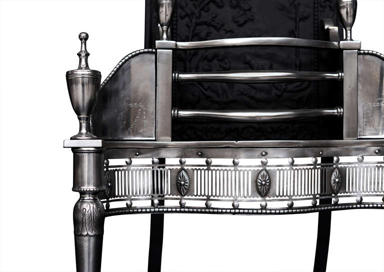 A good quality mid-19th century Georgian style steel fire grate. The fluted fret with cut oval paterae, tapering cylindrical legs with acanthus leaf detailing, urn finials, the side panels engraved with swags and paterae. The shaped cast iron