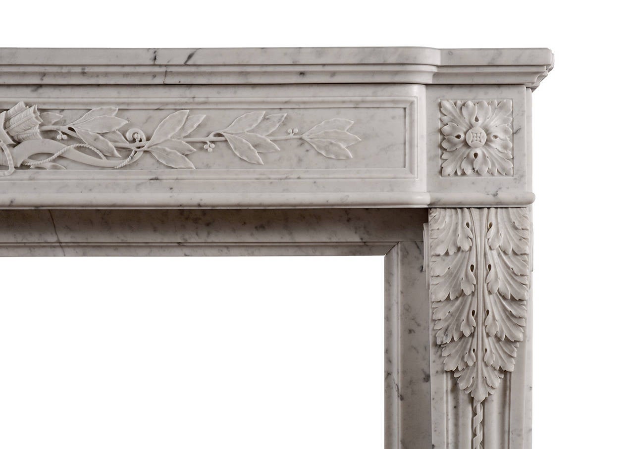 A mid-19th century French Louis XVI style Carrara marble fireplace, with panelled frieze delicately carved with quiver, arrow and foliage. The shaped jambs with acanthus leaves, rope moulding and square paterae above. Panelled returns. Moulded