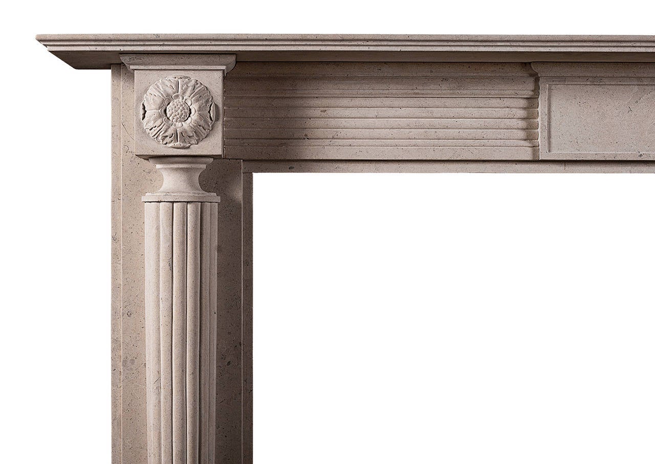 A fine quality English Regency style fireplace in Lincolnshire limestone. The jambs with tapering reeded columns surmounted by end blockings with carved pateras. The reeded frieze with panelled centre tablet. A copy of a period original (circa