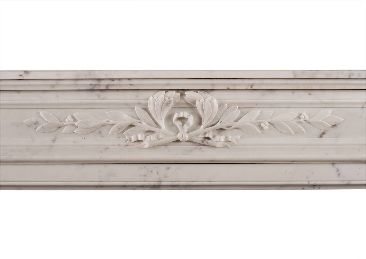 A 19th century French Louis XVI style Carrara marble fireplace. The panelled frieze carved with laurel leaves, the demi lune jambs with flutes inlaid with carved husks, surmounted by carved leaf paterae. Shaped shelf.

Shelf Width - 1546 mm    60