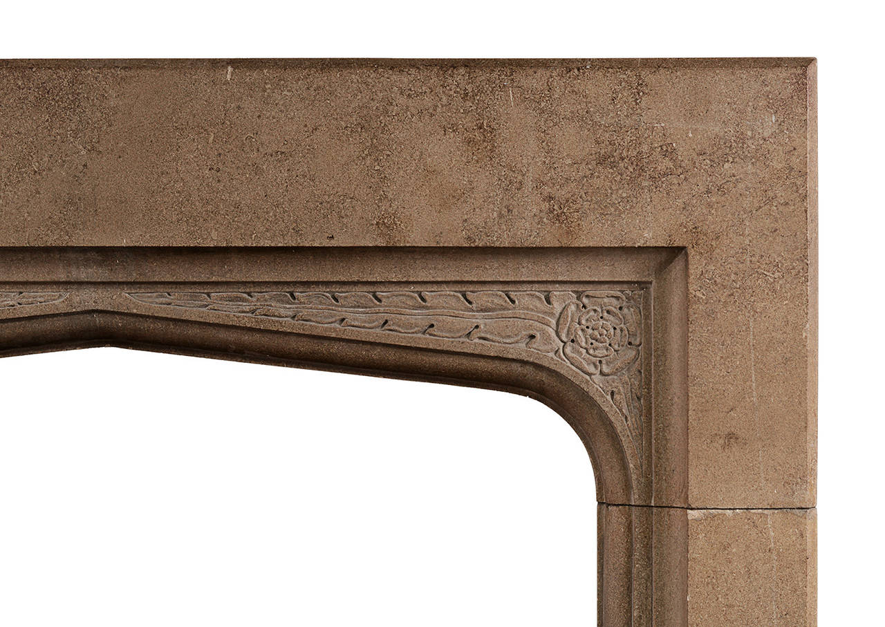 An English Gothic Revival stone fireplace. The spandrels carved with foliage and flowing ribbon. Late 19th century. Warm coloured stone, with a slight wax luster to it. (This could be removed if required.)

Shelf Width - 1524 mm    60  in
Overall