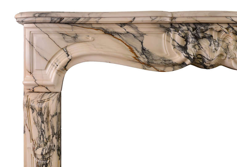 A beautiful Louis XV chimneypiece in sumptuous Italian Pavonazzo marble. The warm veined marble frieze with carved centre shell, shaped panelled jambs, and serpentine moulded shelf. Original bronze vents to jamb returns. French, 19th