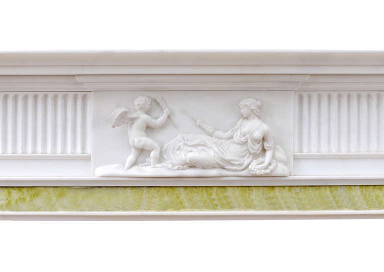 A well proportioned English Georgian fireplace. The fluted frieze with center block of reclining Venus and winged Cupid, the side blockings with the Cupid playing musical instrument. The jambs with curved fluted pilasters. Moulded shelf. The