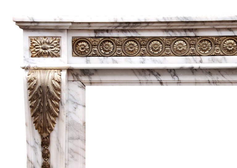 A 19th century French Louis XVI style Arabescato marble fireplace. The frieze enriched with ormolu guilloche, the jambs with ormolu acanthus leaves leading to laurel leaf centre moulding, surmounted by rectangular pateras. Breakfront shelf. (Some