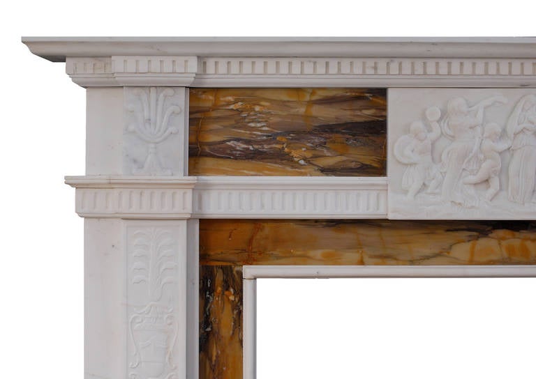 A 19th century English statuary and Sienna marble fireplace in the neoclassical style. The finely carved jambs with Athenian foliage and urns surmounted by carved end blockings. The frieze with carved centre blocking featuring female figures and