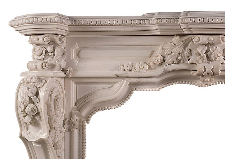 A very impressive French Rococo fireplace carved in statuary marble. The panelled frieze and bracketed jambs delicately carved with trailing flowers and foliage. The serpentine shaped opening with beaded detailing, the shaped moulded shelf with