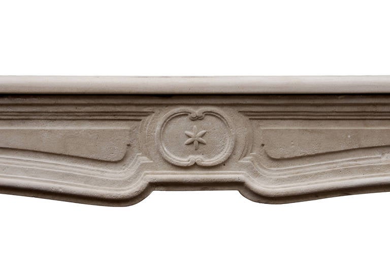 An unusual 18th century French limestone fireplace, of the transitional Louis XIV/XV period. The elegantly shaped frieze with round motif to centre with star within. Shaped fluted jambs and shaped shelf.

Measurements:
Shelf Width:	1600 mm      	63