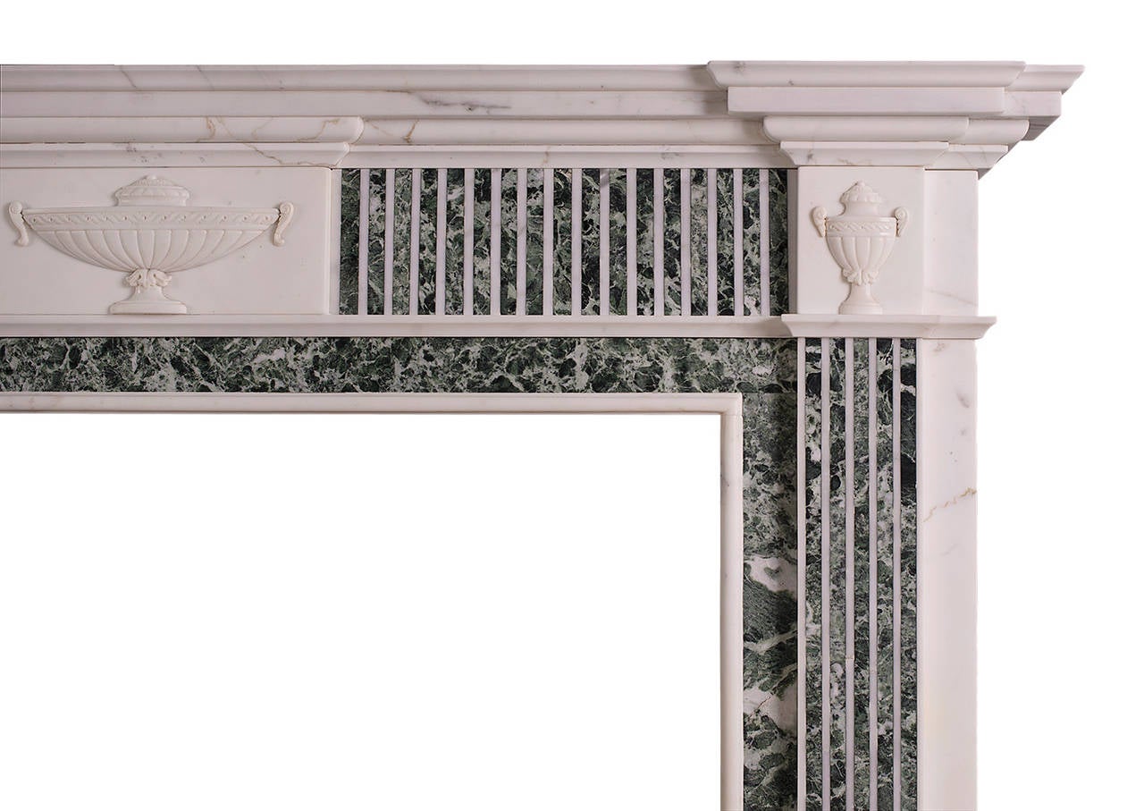 A Georgian style statuary marble fireplace with inlaid green Tinos marble fluting. The centre tablet and side blockings with carved Adam style urns with Vitruvian scroll detailing, English, late 19th century.

Measures: 
Shelf width: 1700 mm / 66