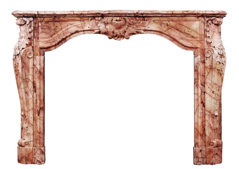 An 18th century, French transitional Louis XIV/XV marble fireplace. The shaped frieze with cartouche centre with scrolls and leaves, juxtaposed by moulded panels. The shaped jambs with stiff acanthus leaf and scroll bases, surmounted by leaf, shells