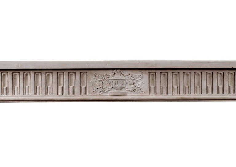 A fine quality period French, Louis XVI style limestone fireplace. The stop-fluted frieze with carved centre panel of urn and foliage with moulding below. The jambs with a pair of tapering stop-flutes surmounted by carved square paterae. Breakfront,
