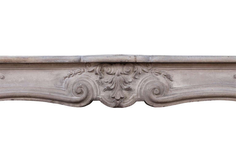 An 18th century, French Louis XV limestone fireplace. The unusually shaped frieze carved with foliage and scrolls to centre and elegant panels to ends, the stop-fluted jambs surmounted by shaped panels. Shaped, moulded shelf.

Measurements:
Shelf