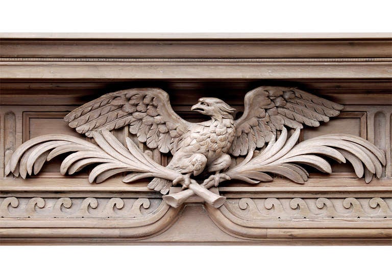 Ein neoklassizistischer englischer Kamin aus Kiefernholz. Der Fries mit einem gut geschnitzten Adler als Mittelstück, daneben Kanneluren und Platten. Darunter verlaufende vitruvianische Schriftrollen. Die Pfosten mit konisch zulaufenden,