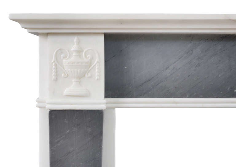 A petite Regency fireplace in statuary and grey Bardiglio marble. The frieze with carved centre placed featuring Adam style urn and drapery. The tapering jambs surmounted by carved with and bell flowers. Moulded shelf above, 19th century.

Shelf