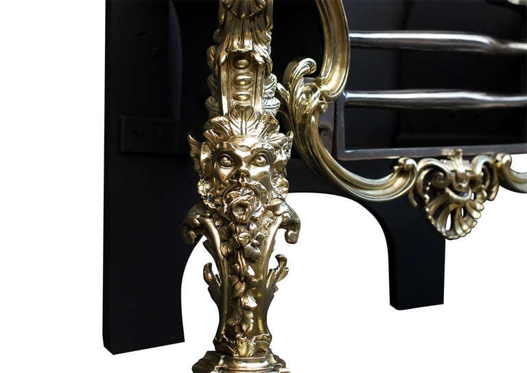 A very fine late 19th century Rococo style brass and steel firegrate. The ornate brass legs with heraldic mask and foliage surmounted by urn finial. The shaped front with scrolls and shell and shaped steel front bars. Decorative shaped cast iron