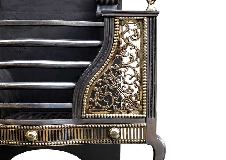 A very good quality Regency brass and steel fire grate. The shaped feet surmounted by fluted, pierced fret and plain paterae. The shaped front bars flanked by decorative brass beaded panels of floral form, with urn finials above. Polished steel flat
