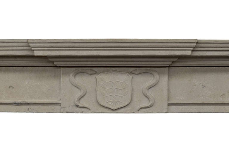 A 19th century English limestone fireplace, with armorial shield to centre, flanked by serpents, plain moulded frieze with tapering pilasters to jambs, and moulded breakfront shelf.

Measures
Shelf Width:	1745 mm      	68 3/4 in
Overall Height:	1395