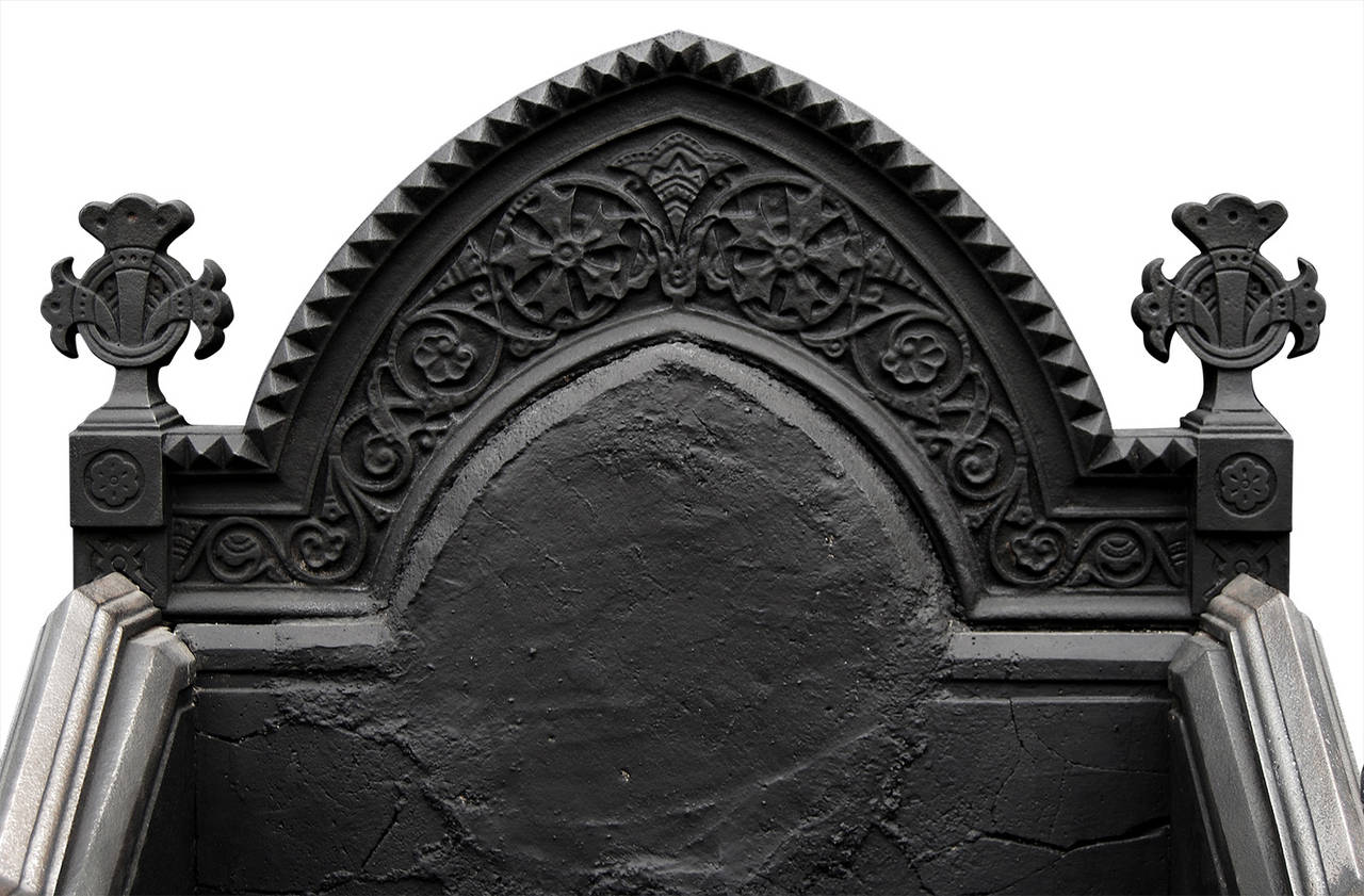 A rare and impressive 19th century (circa 1870) cast iron and gunmetal Neo Gothic fire grate. The dogs ornately cast with gunmetal enrichments, scrolls and round finial tops. Decorative front with shaped ornately cast back. This fire grate is from