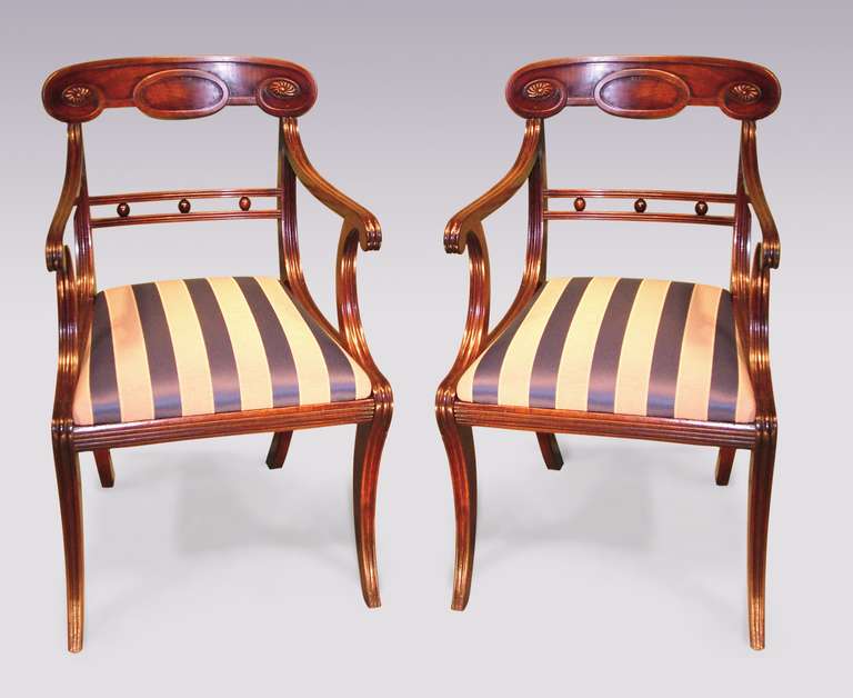 A pair of Regency period mahogany armchairs having moulded curved toprails with carved paterae above ball decorated crossrails. The chairs, finely moulded throughout above drop-in seats supported on sabre legs.