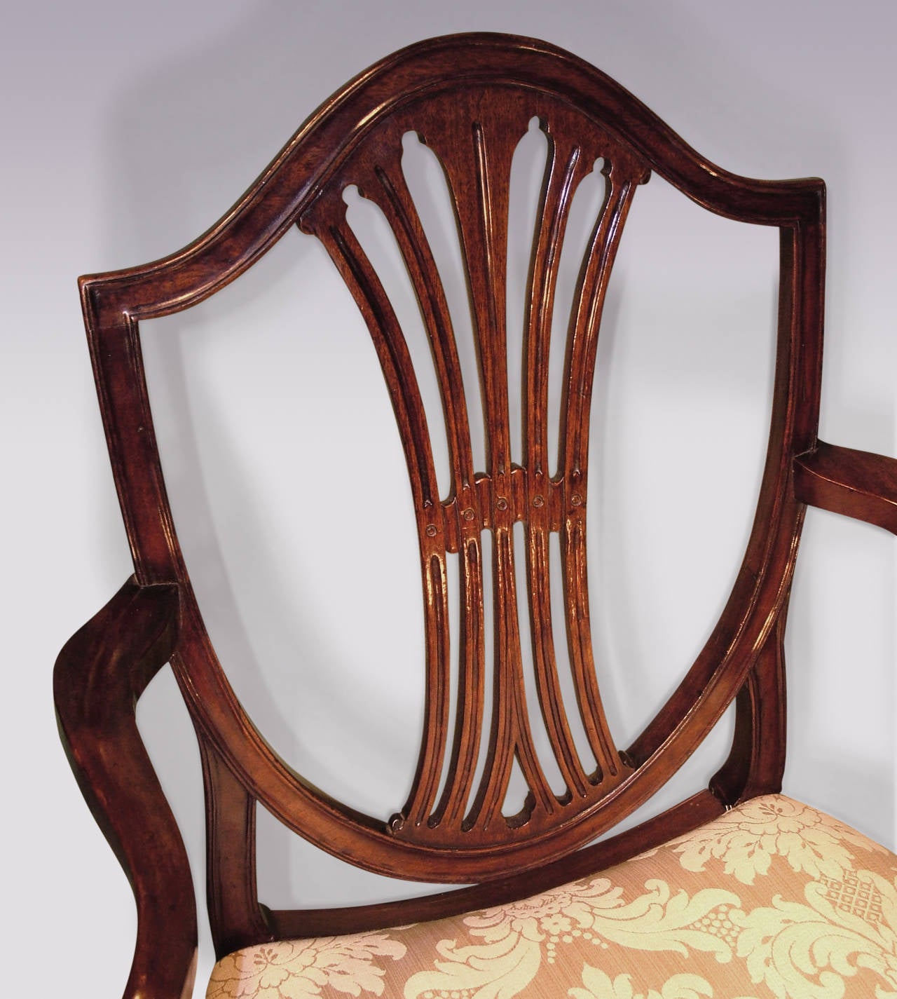 A set of six single and two-arm late 18th century Hepplewhite period mahogany dining chairs, having moulded shield shaped backs with carved central splats and shaped set back arms, above saddled seats supported on moulded square tapering legs. (One