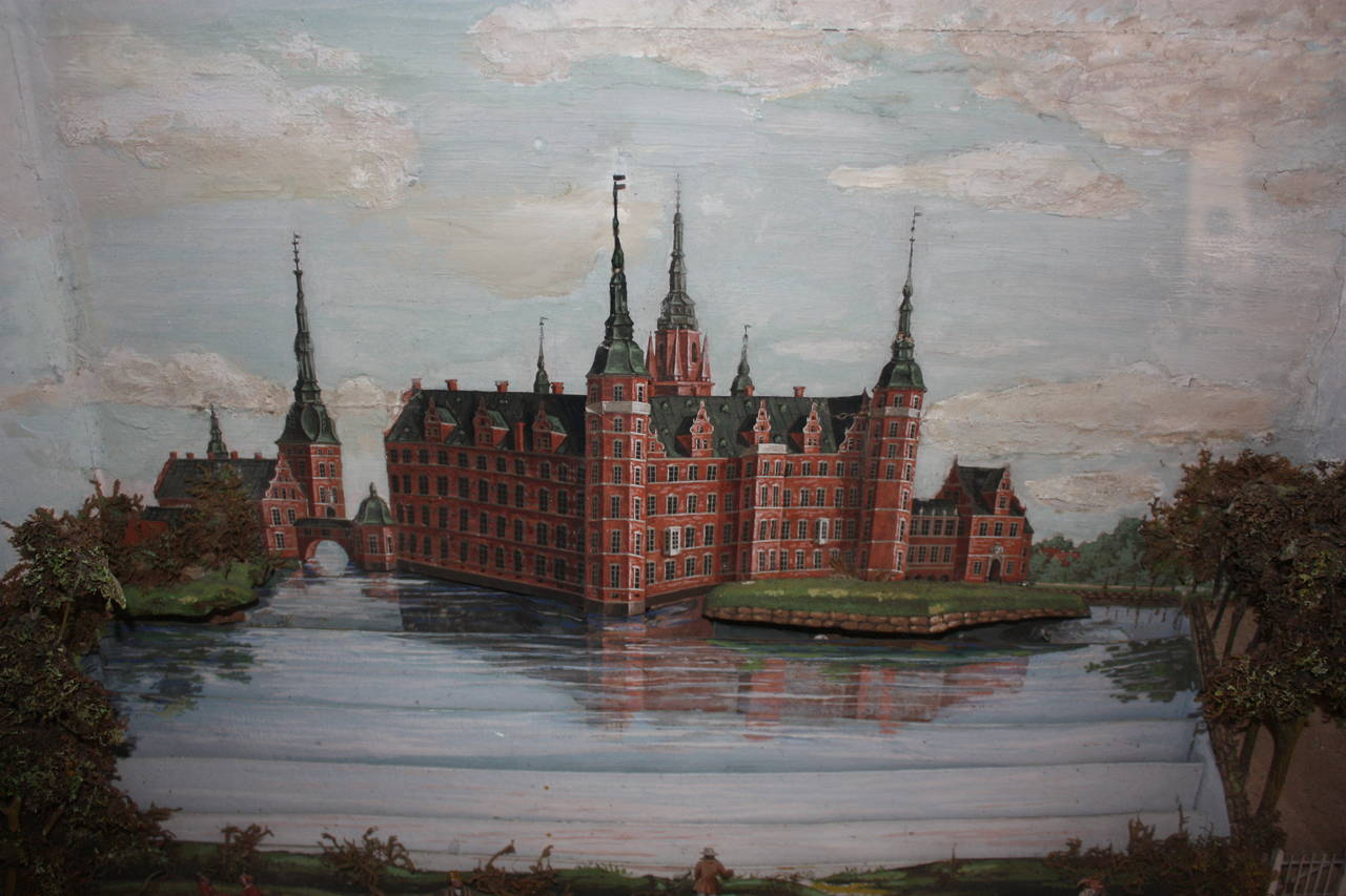 Amazing Danish model representing a scene with three-dimensional figures of Frederiksborg castle and gardens. With miniature people and trees in the foreground and the castle cut to stand out of the background.