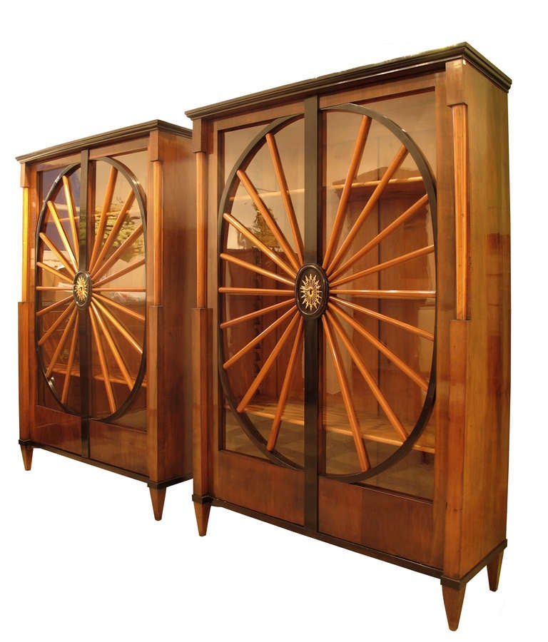A pair of early Biedermeier Danube Monarchy bookcases / vitrines from around 1820-1825. The pair is made of massive and veneered pearwood and diverse fruitwoods. The eye-catching maple bars are orientated in a central sun like figure and finished