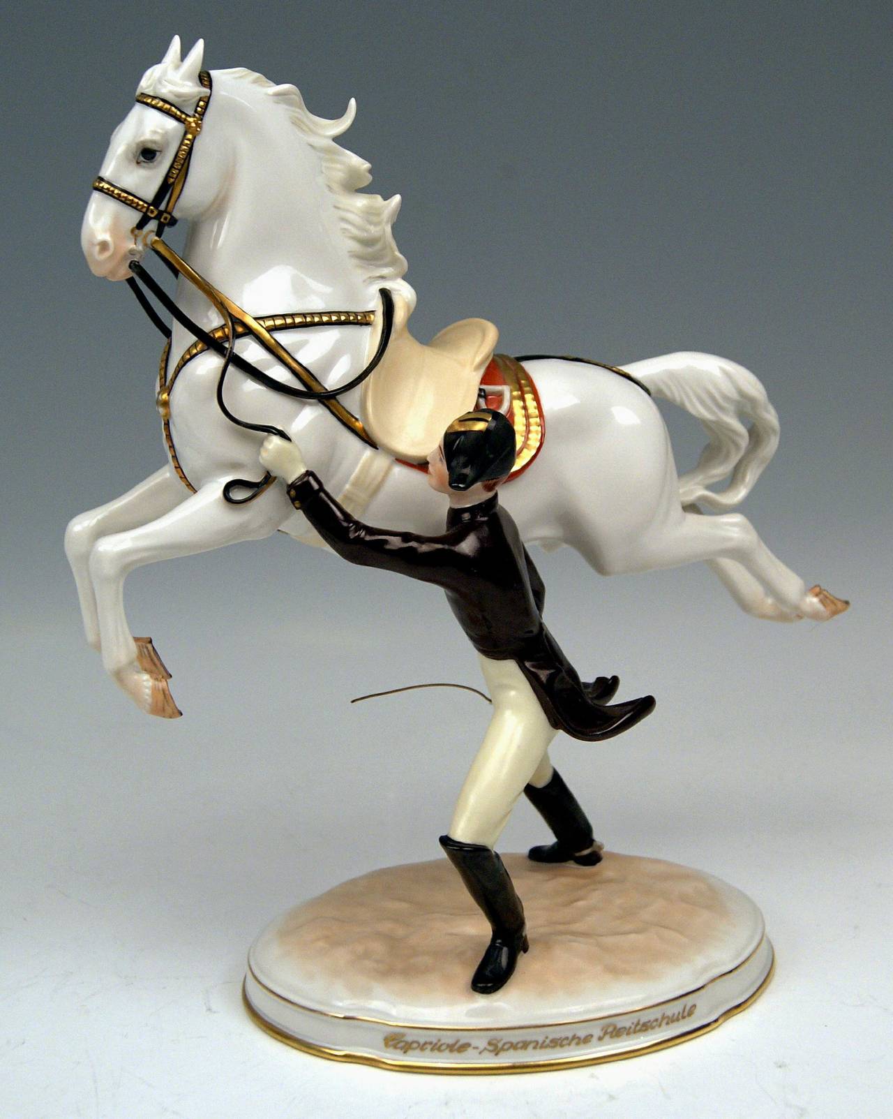 Vienna Augarten Horse Spanish Riding School
Figurine Type:  Capriole

The rider  -  conducting the horse by the reins  -  stands beside the jumping white Lipizzan; he seizes a cane which he needs for horse training .
The jumping horse depicts a