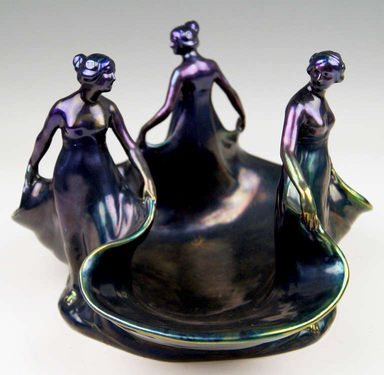 ZSOLNAY VINTAGE LARGE ART NOUVEAU EOSIN BOWL WITH THREE SCULPTURED FEMALE FIGURINES.
Stunning ceramics bowl with gorgeous  EOSIN GLAZE  shining blue-violet-green. The three-sided bowl has extremely scalloped edges from which three sculptured female