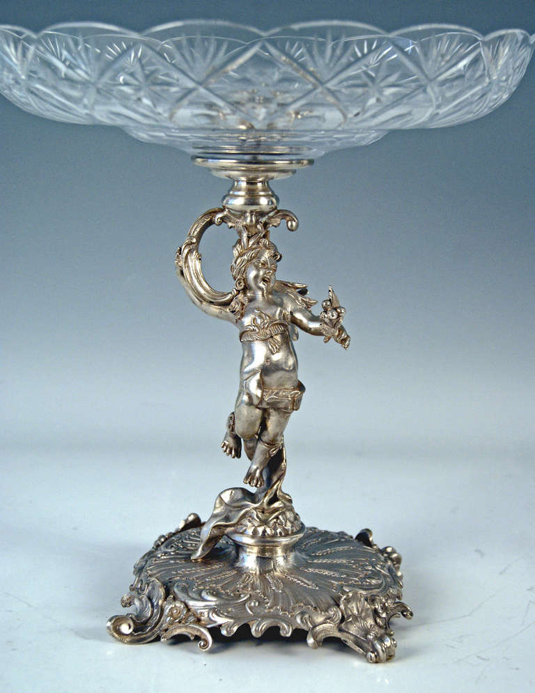 SILVER AUSTRIAN  HISTORICISM TALL CENTREPIECE WITH ORIGINAL GLASS PLATTER    /   MADE CIRCA 1880-90
The stalk of centrepiece is stunningly manufactured:
It is a lovely female long-haired elfin   ( = a sculptured figurine )   holding the glass