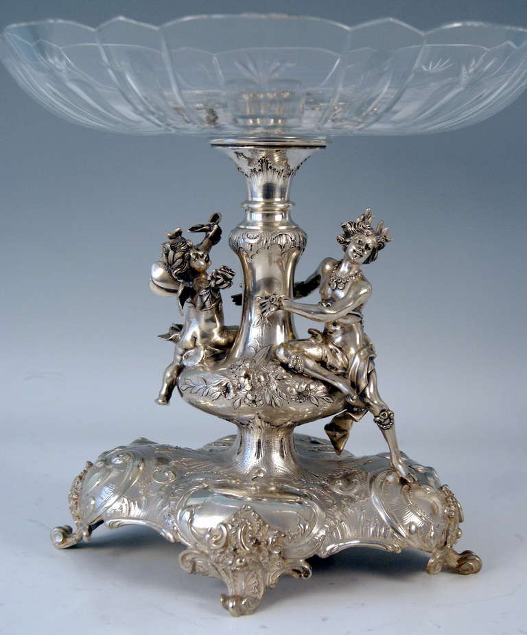 Silver Austrian  Historicism Tall Centerpiece with Glass Platter, circa 1880-1890. The stalk of centerpiece is stunningly manufactured. 
There are lovely sculptured figurines surrounding stalk:  It is a male elfin  holding a rose flower in right