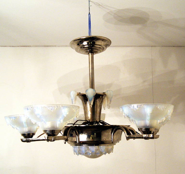 Stunning Art Deco chandelier with five arms made in France, circa1930.
The bulbs are enclosed by opaline white frosted glass shades of very elegant form type. The chandelier’s arms are connected to each other by chromium-plated struttings being