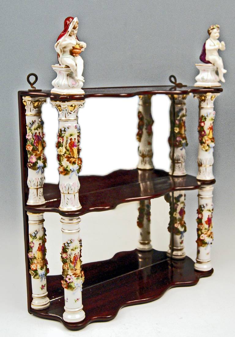 Wooden shelves supported by porcelain figurines and columns, most probably made by Dresden Porcelain Manufactory during second half of 19th century, decorated with cherubs at top piece: The figurines are strongly influenced by models which had once