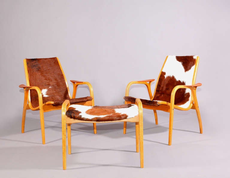 Two lamino armchairs with ottoman,
Designed Ingve Ekström
Sweden, 1956,
Laminated beechwood,
Three-color cowskin.
Measures: Chairs height 80cm, widht 70cm, depht 70cm, seatheight 41cm.
Foodstool height 48cm, widht 60cm, depht 46cm.