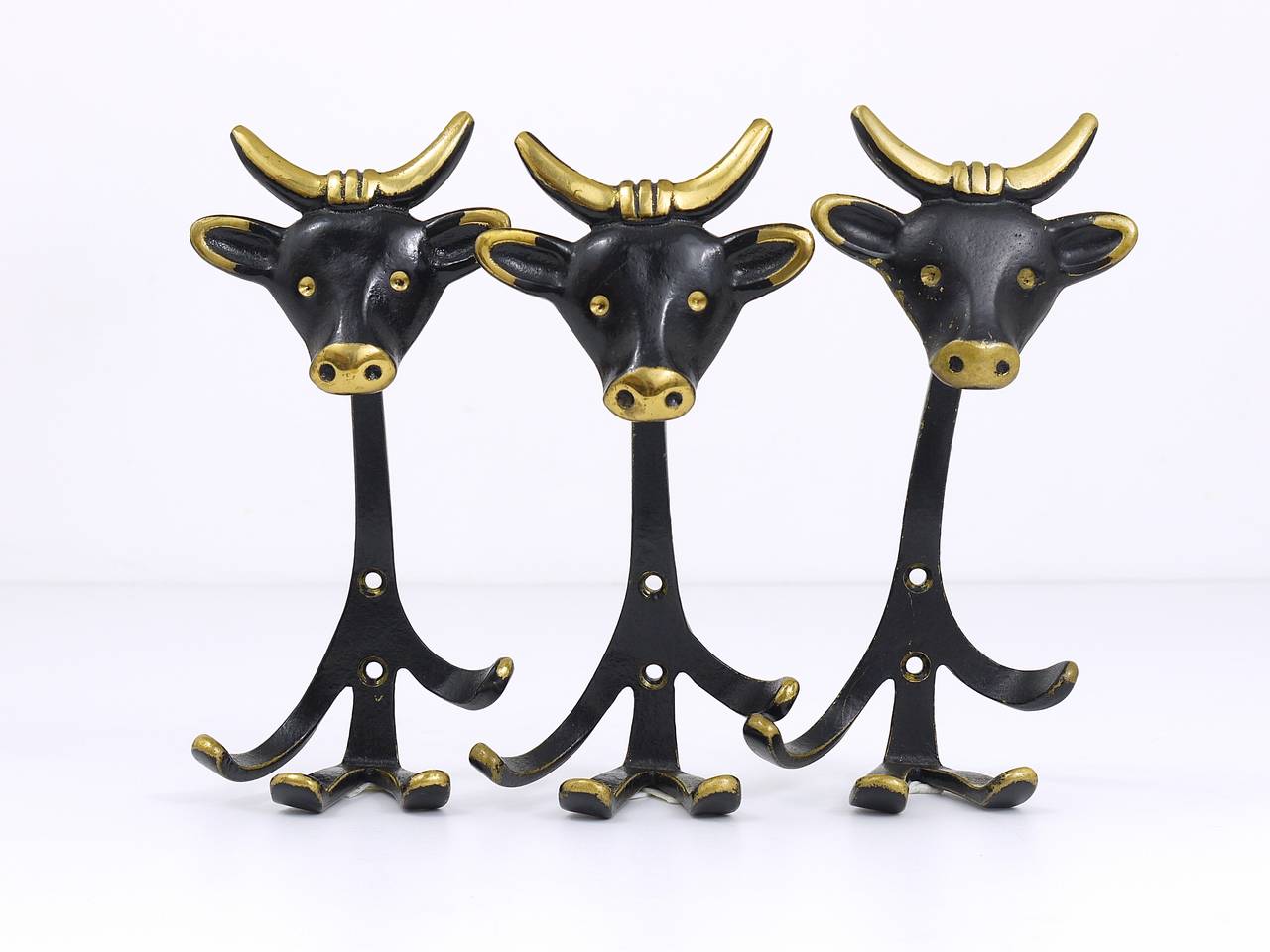 A set of 3 Viennese modernist brass wall coat hooks, displaying a cow. Designed in the 1950s by Walter Bosse, executed by Baller Vienna. Made of black finished brass. In very good condition with nice patina. Each hook has a height of 7