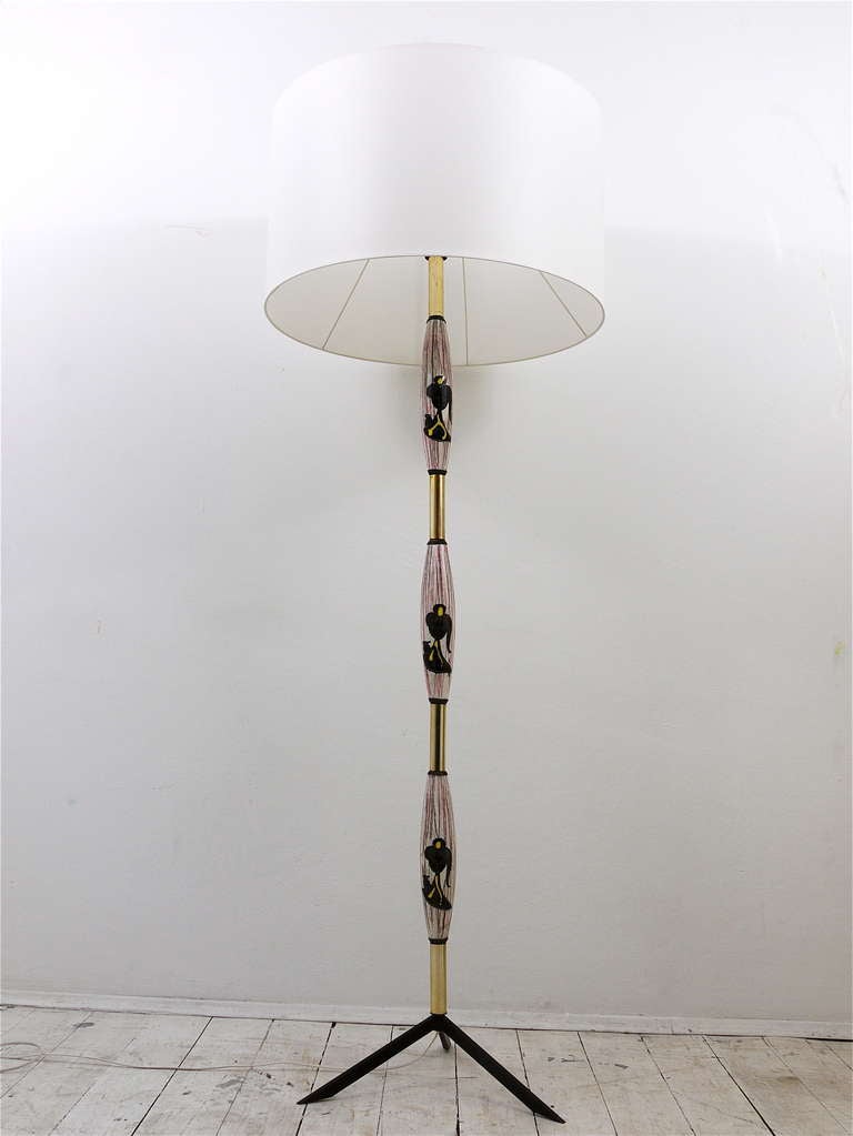 A beautiful and elegant Italian modernist floor lamp from the 1950s. A charming piece, with lovely hand painted ceramic details on its neck and  a tripod star base. In very good condition with nice patina on the brass pieces. 66 inches high, the